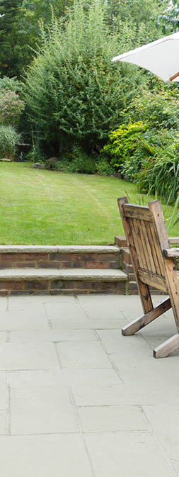 London garden in summer with patio, wooden garden furniture and a parasol or sun umbrella
